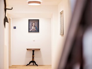 A hallway with a framed artwork on the wall, a small table, and a door marked with the number 3.