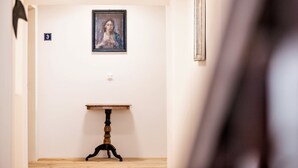 En gang med et indrammet kunstværk på væggen, et lille bord og en dør med nummer 3.