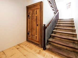 A wooden staircase with a handrail and a wooden door with decorative elements.