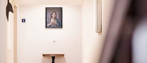 Un pasillo con una obra enmarcada en la pared, una pequeña mesa y una puerta con el símbolo del número.