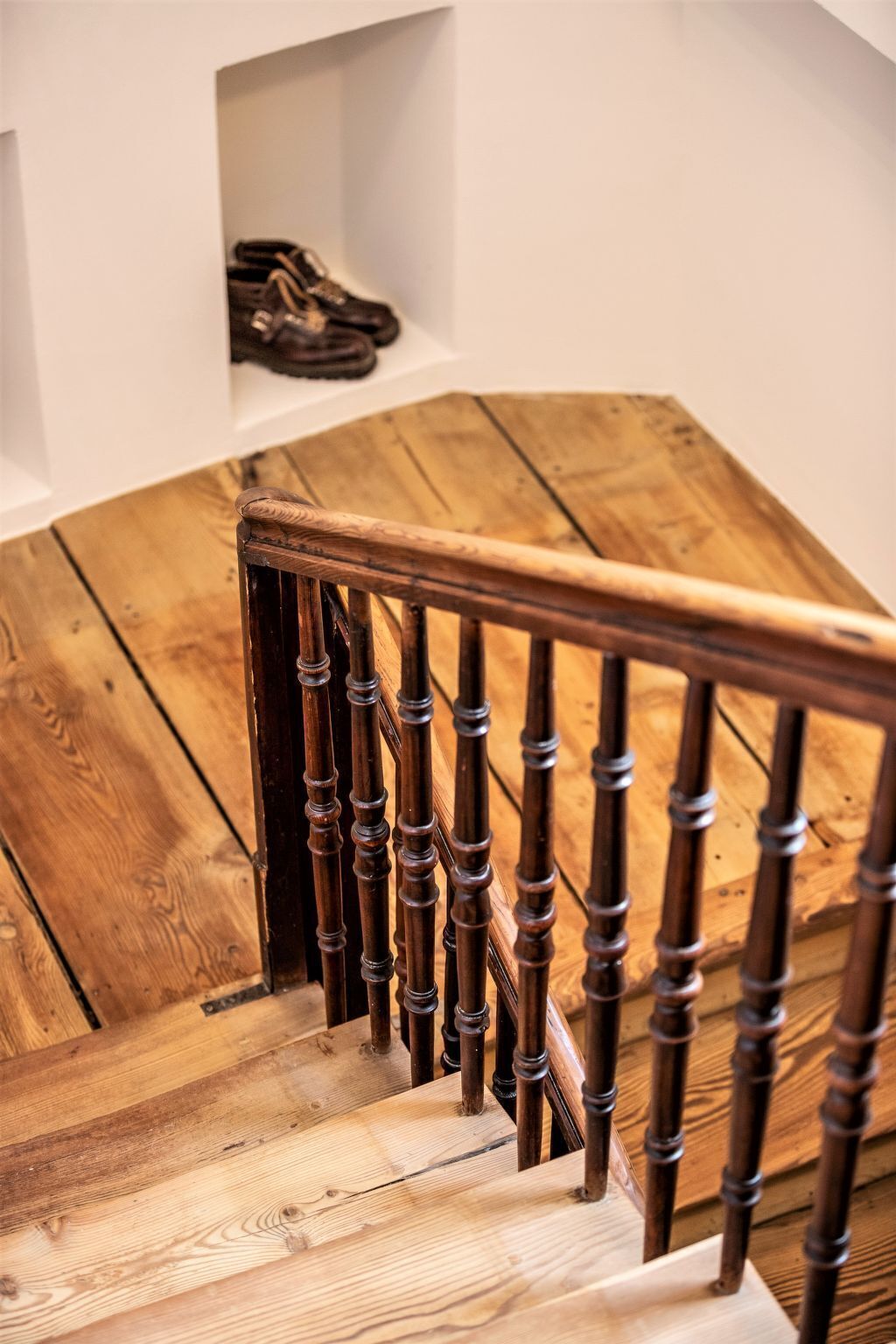 A wooden staircase with a handrail and a white wall above.