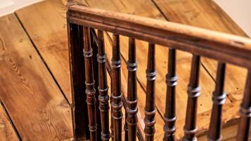 A wooden staircase with a handrail and a white wall above.