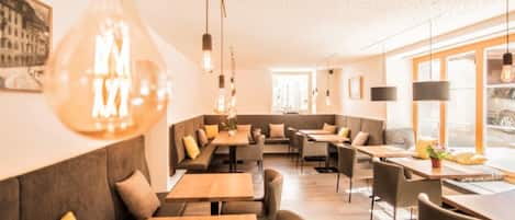 Ein modernes Interieur mit Sitzbereichen, Tischen und hängenden Leuchten.