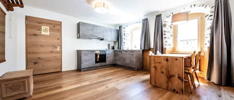 Une cuisine moderne avec un plancher en bois, un four encastré et des armoires grises.