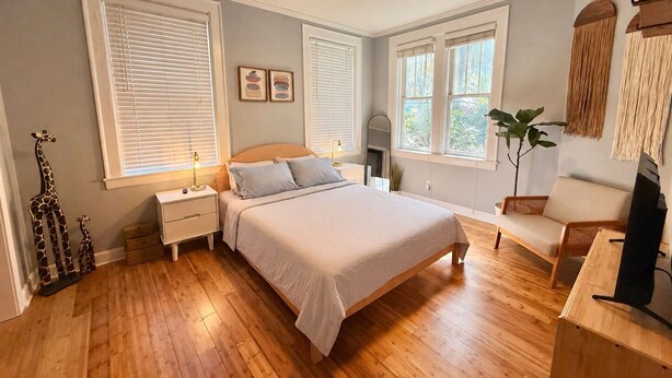 Ein Schlafzimmer mit einem Bett, Nachttischen, einem Deckenventilator und großen Fenstern.