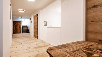 Ein Flur mit Holzboden, einer Holztür und einer Treppe, die in ein weiteres Zimmer führt.