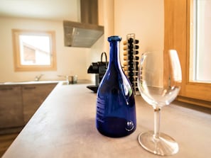 Una encimera de cocina con una botella azul, una copa de vino y una máquina de caf é.