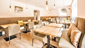 L’intérieur d’un restaurant, avec des banquettes, des tables, des luminaires suspendus et une sculpture d’oiseau fixée au mur.