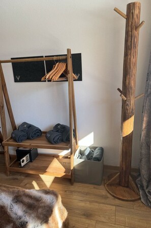 A wooden coat rack with a blackboard, a wooden shelf with folded towels, and a storage box on the floor. - Berg-Bijou Scuol, (Scuol) by Interhome (Scuol)
