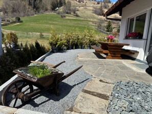 Un patio con un carretilla, una mesa de madera y un sendero de piedra.