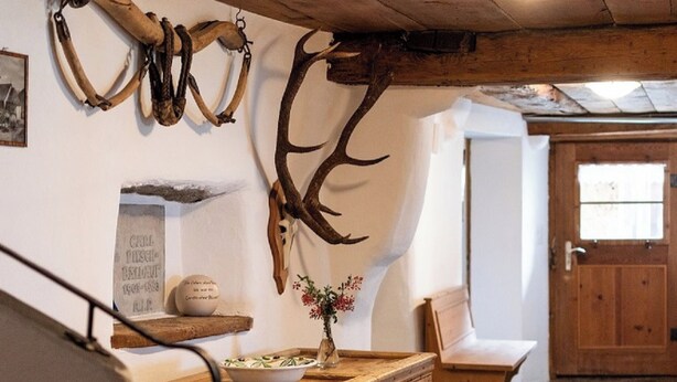 A rustic interior with wooden beams, antlers on the wall, a wooden cabinet, and a bench. - Agrotourismus Pütschai Josom, (Sta. Maria - Santa Maria Val Müstair) by Interhome (Sta. Maria GR)
