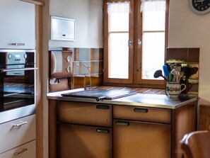 A kitchen with a stove, oven, and a window with a view. - Agrotourismus Pütschai Josom, (Sta. Maria - Santa Maria Val Müstair) by Interhome (Sta. Maria GR)
