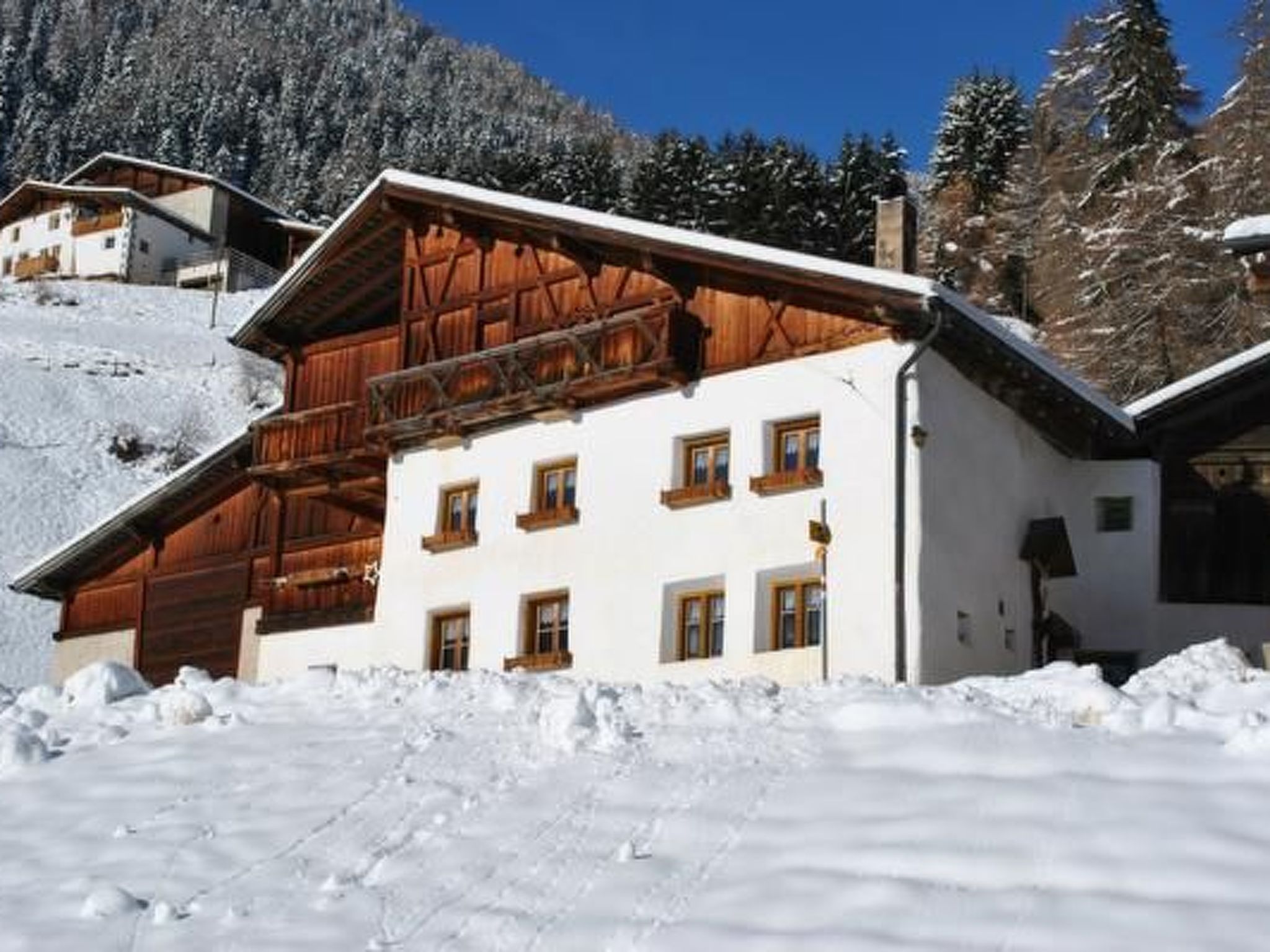A multi-story building with a wooden facade and multiple windows, surrounded by snow-covered terrain and trees.
