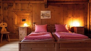 A wooden cabin with two beds, a wooden chair, a small table, and a framed picture on the wall. - Agrotourismus Pütschai Josom, (Sta. Maria - Santa Maria Val Müstair) by Interhome (Sta. Maria GR)