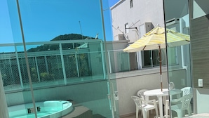 Un balcone con una porta vetrata, un tavolo rotondo e un ombrellone a righe gialle.