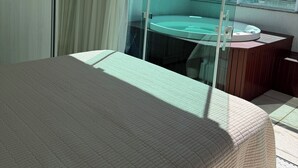 Camera d'hotel con un letto grande, un tavolino rotondo e vista sulla città attraverso un'ampia finestra.