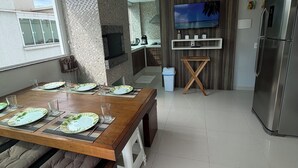 Una cucina moderna con zona pranzo, TV a parete e frigorifero in acciaio inox.