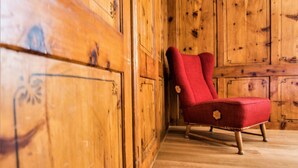 Ein Zimmer mit Holzboden, einem roten Sessel und einem Holzschrank.