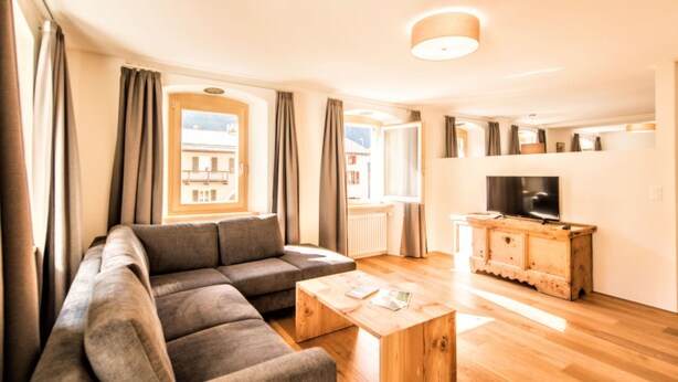 Ein modernes Wohnzimmer mit einer Couch, einem Couchtisch, einem Fernseher und einer Holzkassette.