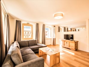 Een moderne woonkamer met een bank, salontafel, televisie en een houten kast.