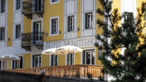 Ein Hotel mit gelber Fassade, Balkonen mit schwarzen Geländern und Coca-Cola-Marken-Schirmen.