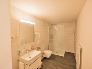 Een moderne badkamer met douche, toilet en wastafel.