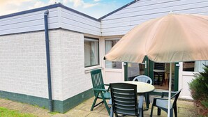A patio with a table and chairs, a covered area, and a brick wall. - Bungalowpark Simpelveld - Schakel 6 by Interhome (Simpelveld)