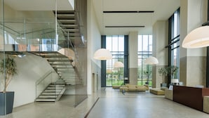 A spacious lobby with a staircase, large windows, and modern lighting. - Unique Bosco Verticale Apartment: Live in the World's Icon (Milano)