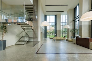 A spacious lobby with a staircase, large windows, and modern lighting. - Unique Bosco Verticale Apartment: Live in the World's Icon (Milano)