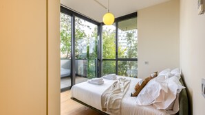 A modern bedroom with a large bed, a balcony, and a view of greenery. - Unique Bosco Verticale Apartment: Live in the World's Icon (Milano)