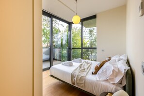 A modern bedroom with a large bed, a balcony, and a view of greenery. - Unique Bosco Verticale Apartment: Live in the World's Icon (Milano)