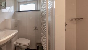 A bathroom with a toilet, sink, and a window above the toilet. - Bungalowpark Simpelveld - Alpha 79 by Interhome (Simpelveld)
