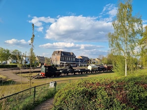 Een treinstation met een stilstaande trein, sporen en een gebouw op de achtergrond.