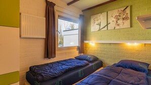 A room with two single beds, a window with curtains, a radiator, and a wall-mounted air conditioner. - Bungalowpark Simpelveld - Schakel 16 by Interhome (Simpelveld)
