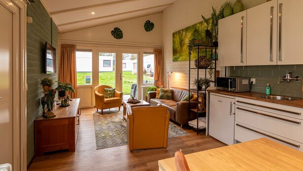 A spacious living area with a sofa, coffee table, and a kitchen with white cabinets and a wooden countertop. - Bungalowpark Simpelveld - Schakel 16 by Interhome (Simpelveld)