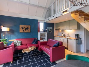 A modern living room with a red sofa set, a small wooden table, and a world map on the wall. - Bungalowpark Simpelveld - Delta 120 by Interhome (Simpelveld)
