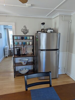 A kitchen with a stainless steel refrigerator, a coffee maker, and a shelf with various mugs and bowls. - Great location to enjoy all that Newport has to offer. (Newport)