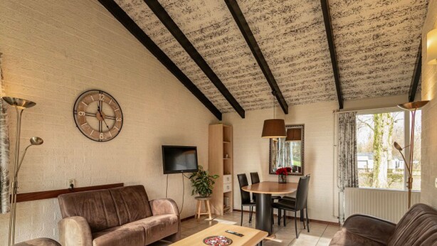Ein Wohnzimmer mit Sofa, Couchtisch, Fernseher und einem Essbereich mit Stühlen und Tisch.