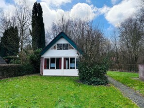 A two-story house with a gabled roof, a front porch, and a pathway leading to the entrance. - Bungalowpark Simpelveld - Delta 154 by Interhome (Simpelveld)