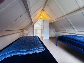 A small, enclosed attic bedroom with a sloped ceiling, a single bed, a chair, and a window. - Bungalowpark Simpelveld - Delta 154 by Interhome (Simpelveld)