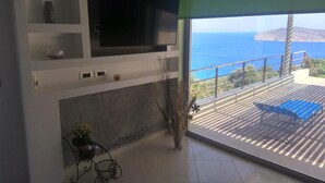 Un saló modern amb un televisor gran, una planta en test i una vista a l'oceà.