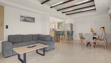 A modern living room with a grey sectional sofa, a wooden coffee table, and a dining area with a table and chairs.