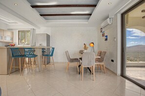 A modern kitchen with a dining area, featuring a large window and a view of the landscape. - Villa 'Gusta' with Sea View, Wi-Fi and Air Conditioning (Thólos)