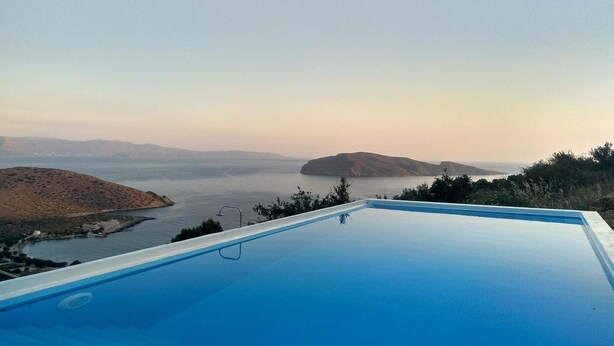 Una piscina amb vistes a un cos d'aigua i les colines llunyanes.