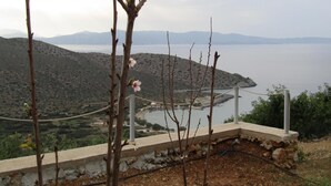 Vista d'un paisatge costaner amb un pont, una massa d'aigua i turons al fons.