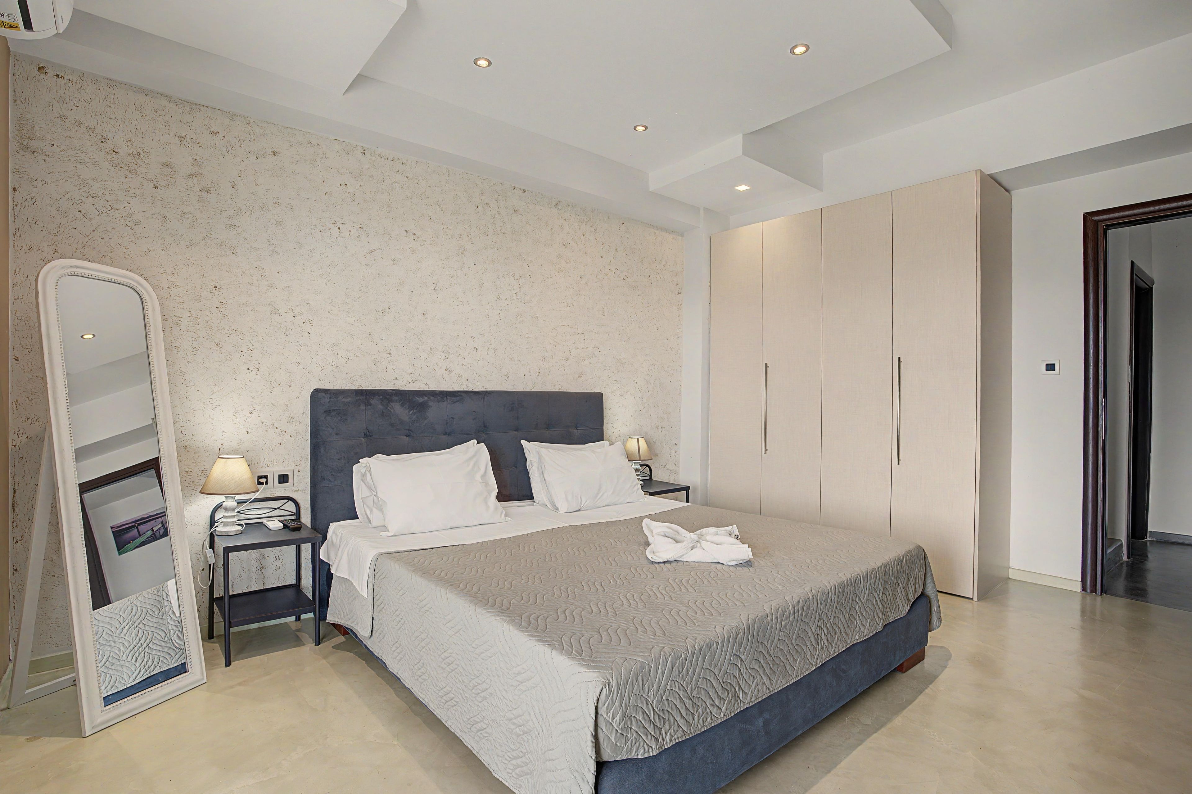 Ein Hotelzimmer mit einem großen Bett, einem Nachttisch, einem Spiegel und einem Kleiderschrank.