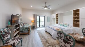 A bedroom with a bed, a TV, a desk, and a chair. - Gorgeous Old Town Bay St Louis Luxury Studio condominium! (Bay St. Louis)