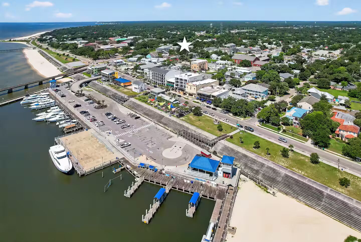 An aerial view of a coastal town with a marina, a bridge, and a star-shaped building.