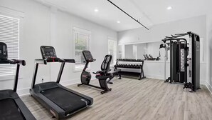 A gym with treadmills, a weight bench, and a squat rack. - Gorgeous Old Town Bay St Louis Luxury Studio condominium! (Bay St. Louis)