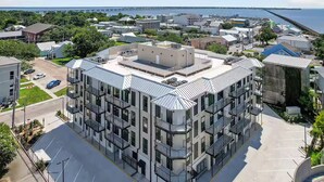 A modern multi-story building with a flat roof, large windows, and balconies. - Gorgeous Old Town Bay St Louis Luxury Studio condominium! (Bay St. Louis)